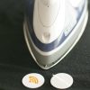 Two iron-on NFC tags next to an iron on a piece of black fabric